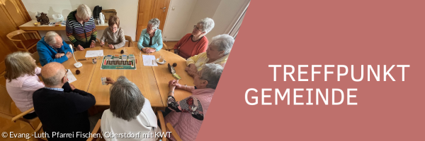 Verschiedene Personen, die miteinander am Tisch sitzen und ein Brettspiel spielen.